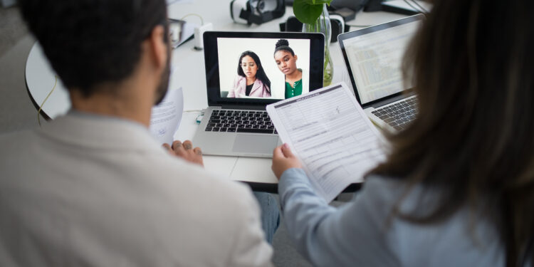 Two personnels from a company interviewing candidates online in a video call
