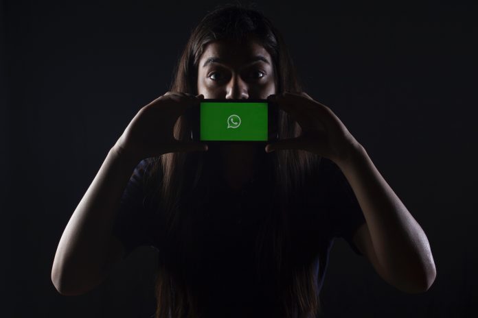rachit-tank-lZBs-lD9LPQ-unsplash A girl holding a smartphone with WhatsApp open