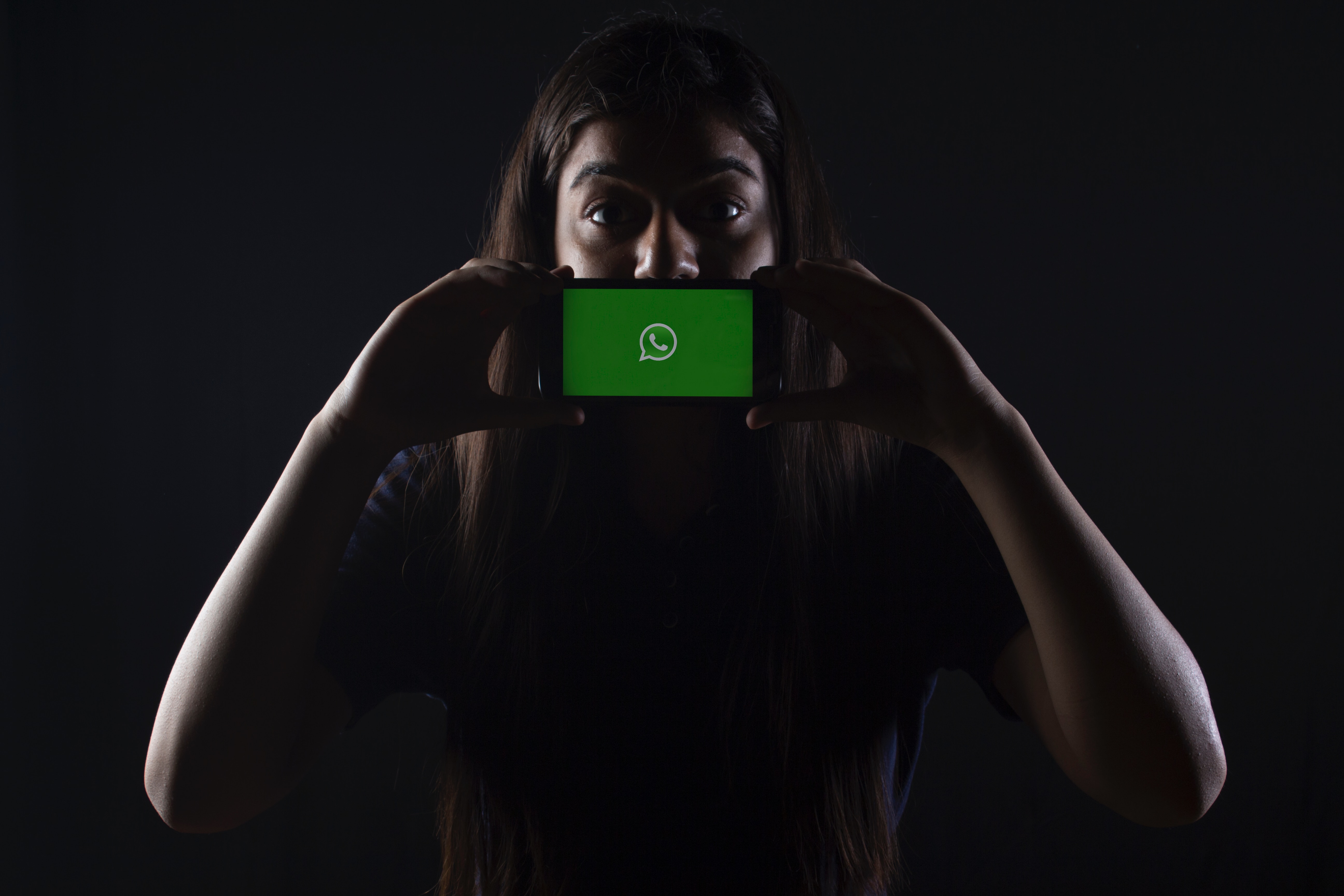 A girl holding a smartphone with WhatsApp open
