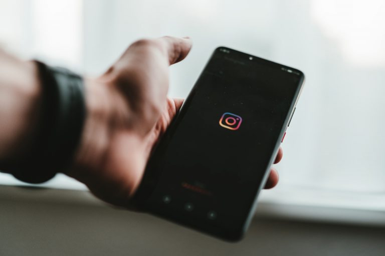 A person holding a phone showing Instagram logo